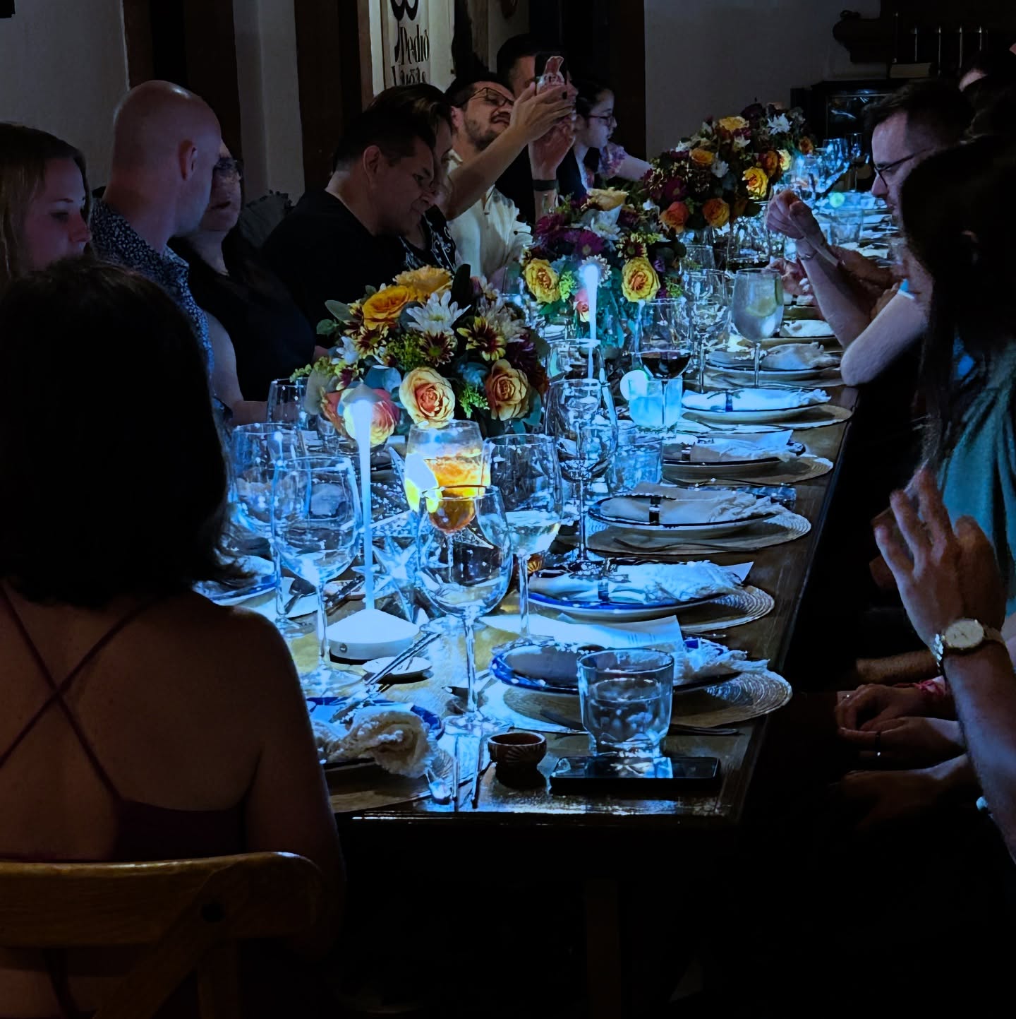 Mesa larga iluminada con velas y flores durante una cena privada