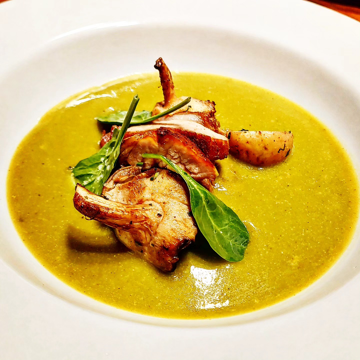 Mole verde con pollo dorado, hongos y hoja santa en plato blanco