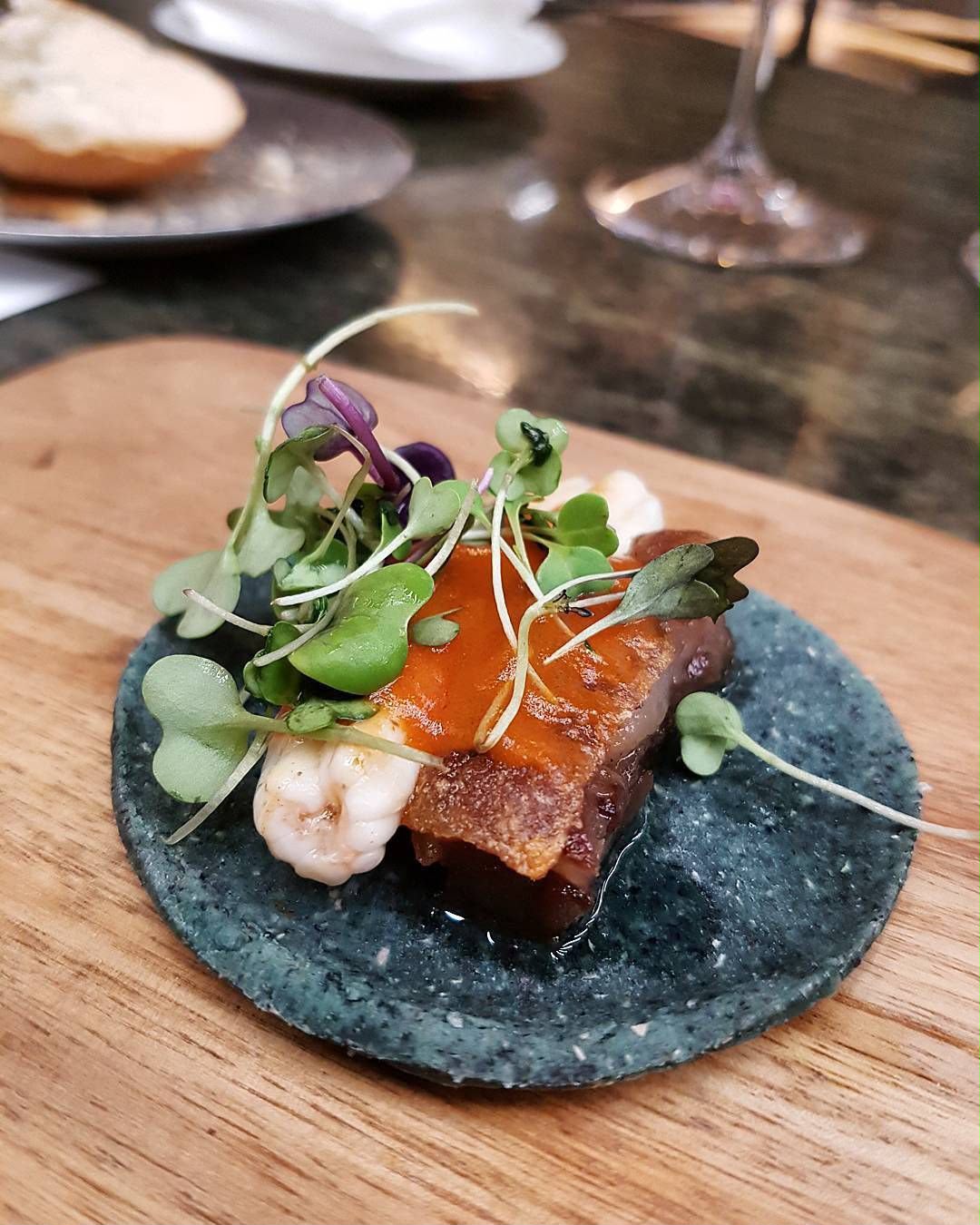 Taco de chicharrón con camarón y microgreens sobre tortilla azul