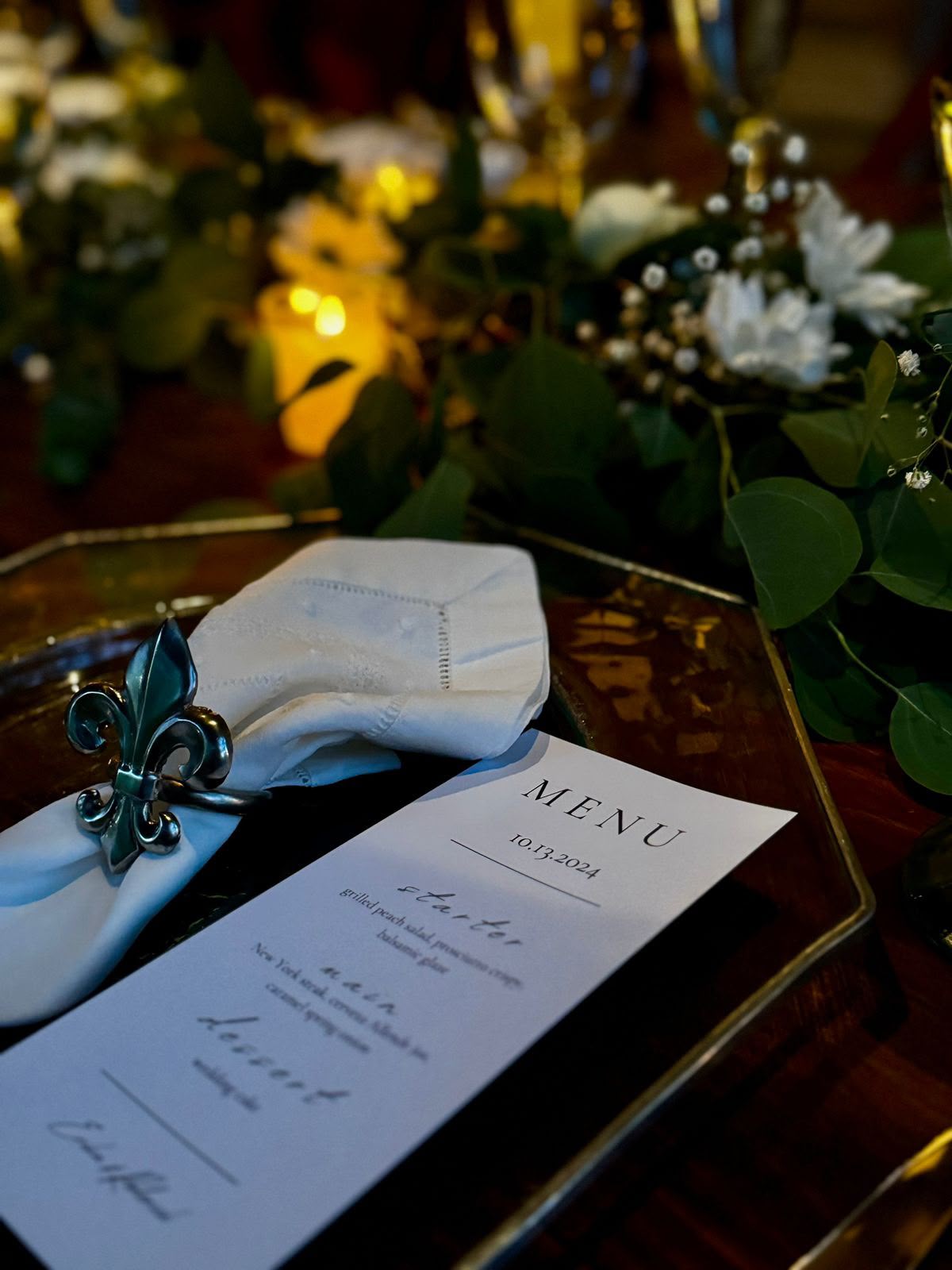 Menú de boda sobre plato dorado con servilleta y velas